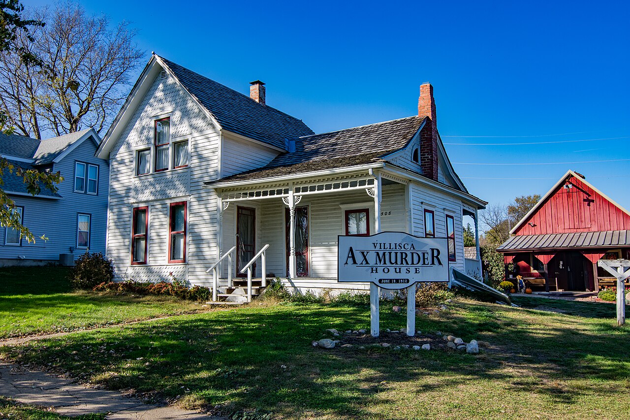 The restored white Villisca Axe Murder House with a sign in the yard